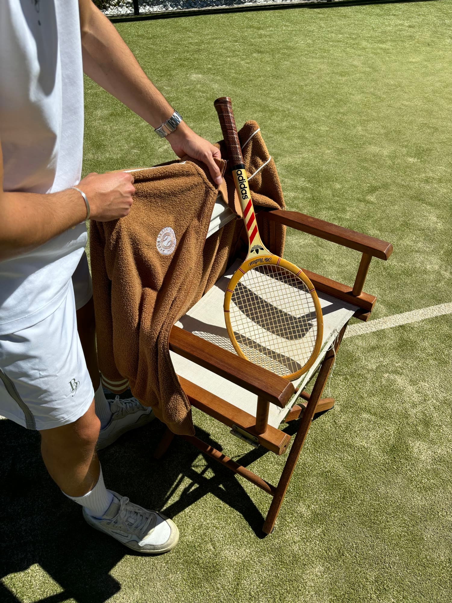 Detalle de toalla marrón y raqueta de madera en silla de juez
